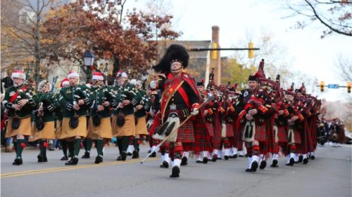 A Scottish bagpipe band marching in a parade on a fall day.