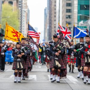 Bagpipers marching down the a street.