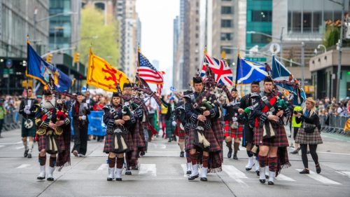 Bagpipers marching down the a street.